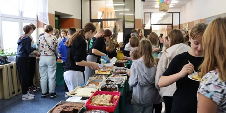 Powiększ grafikę: Na zdjęciu uczniowie przy stoisku z ciastami